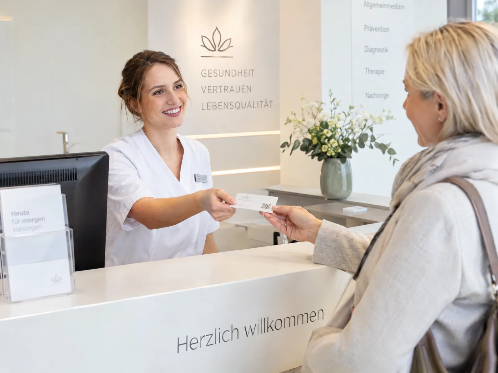 Empfang einer Arztpraxis übergibt eine Terminkarte an einen Patienten